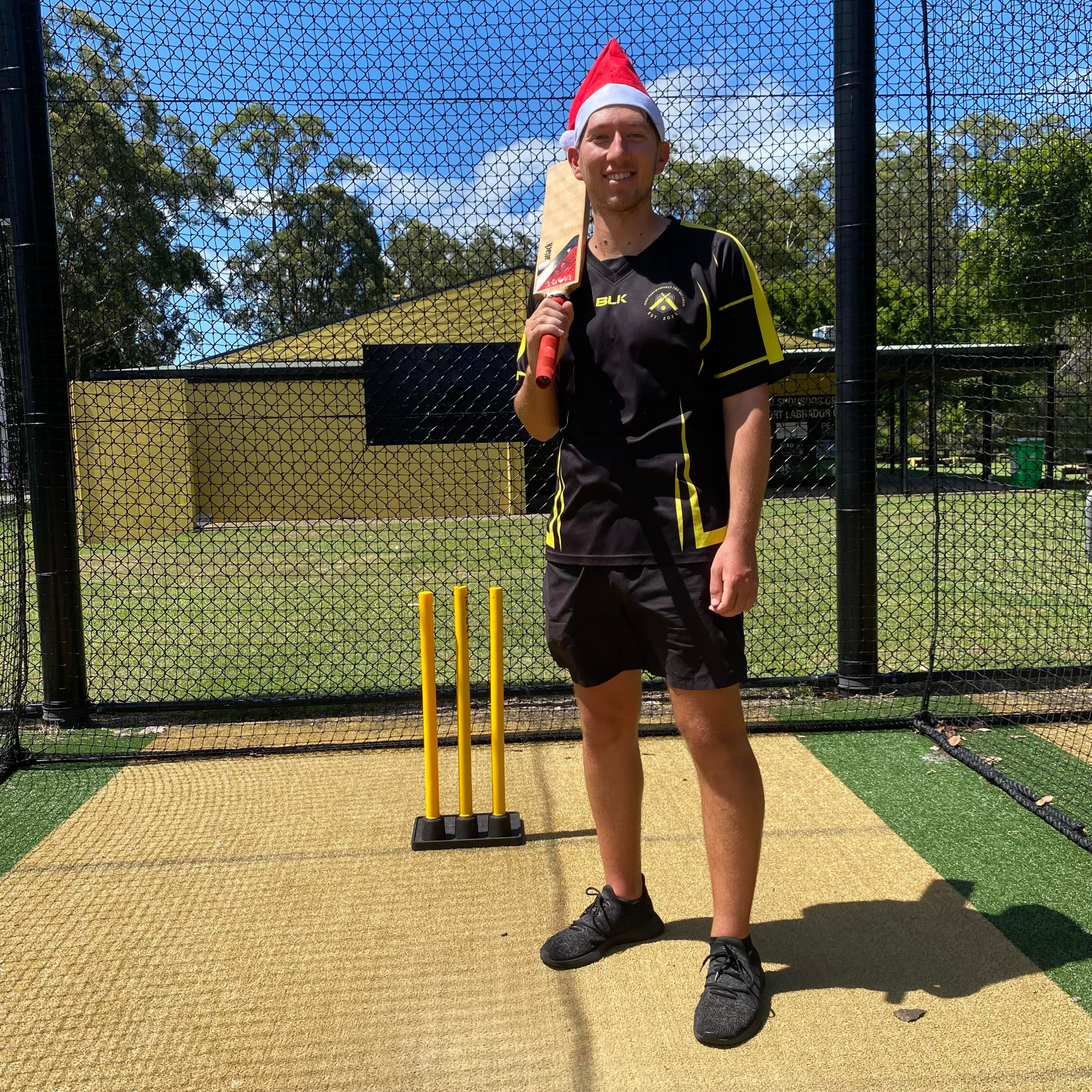 Jarrod in a Santa hat with bat and stumps